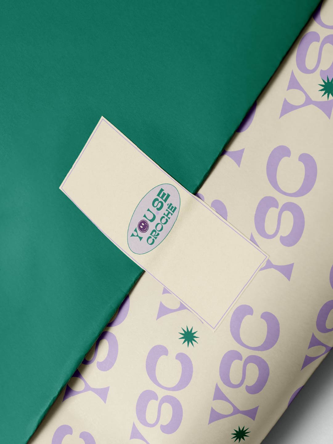 Embalagem da Youse Crochê em verde e creme com padrão tipográfico e selo da marca